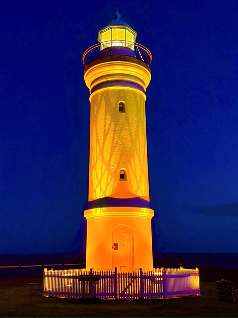 Kiama Lighthouse lit up in yellow