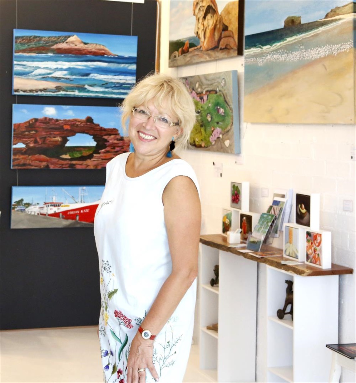 Artist, Iryna White, with her artworks in a gallery setting 
