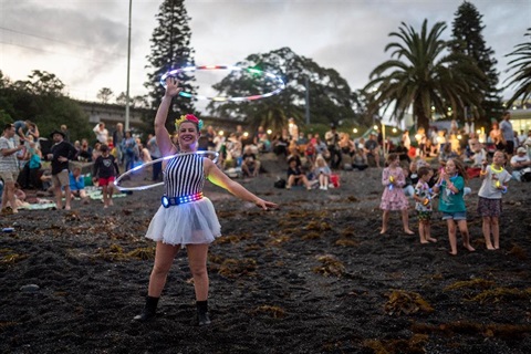 circus performer swirling two hula hoops with crowd in background