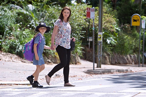 School child and parent check traffic before crossing road